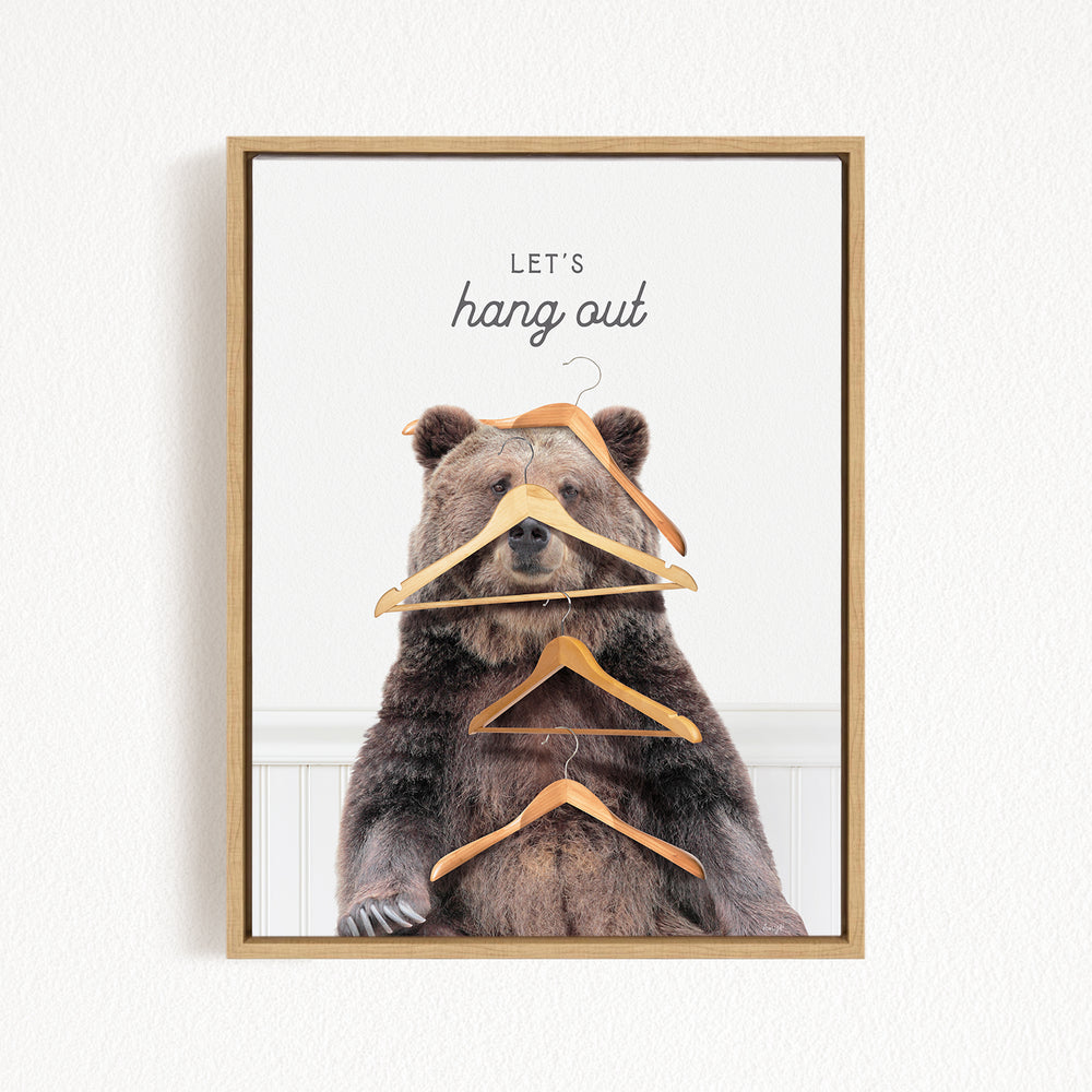 A framed image of a bear sitting on a shelf with multiple wooden hangers hanging from its head and neck.