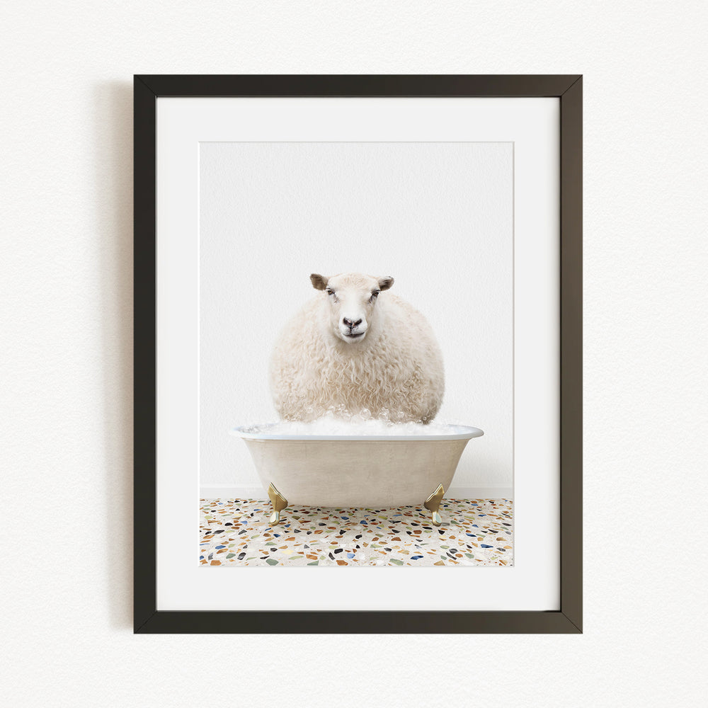 A fluffy white sheep sits in a white bathtub filled with bubbles, creating a whimsical and playful scene.