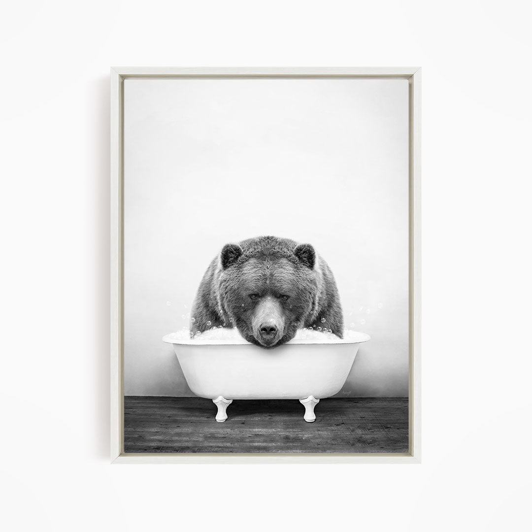 A black and white image of a bear sitting in a bathtub.