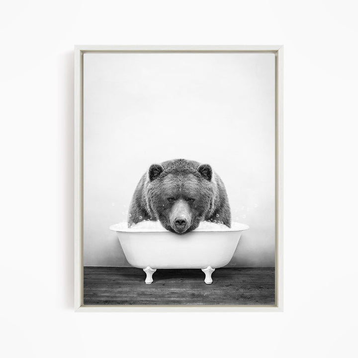 A black and white image of a bear sitting in a bathtub.