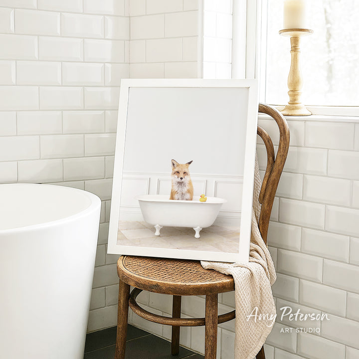 A framed image of a cat sitting in a bathtub, with a yellow rubber duck floating in the water.