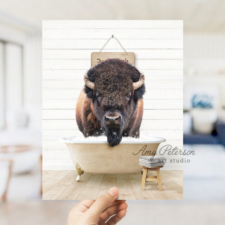 a hand holding a photo of a bison in a bathtub