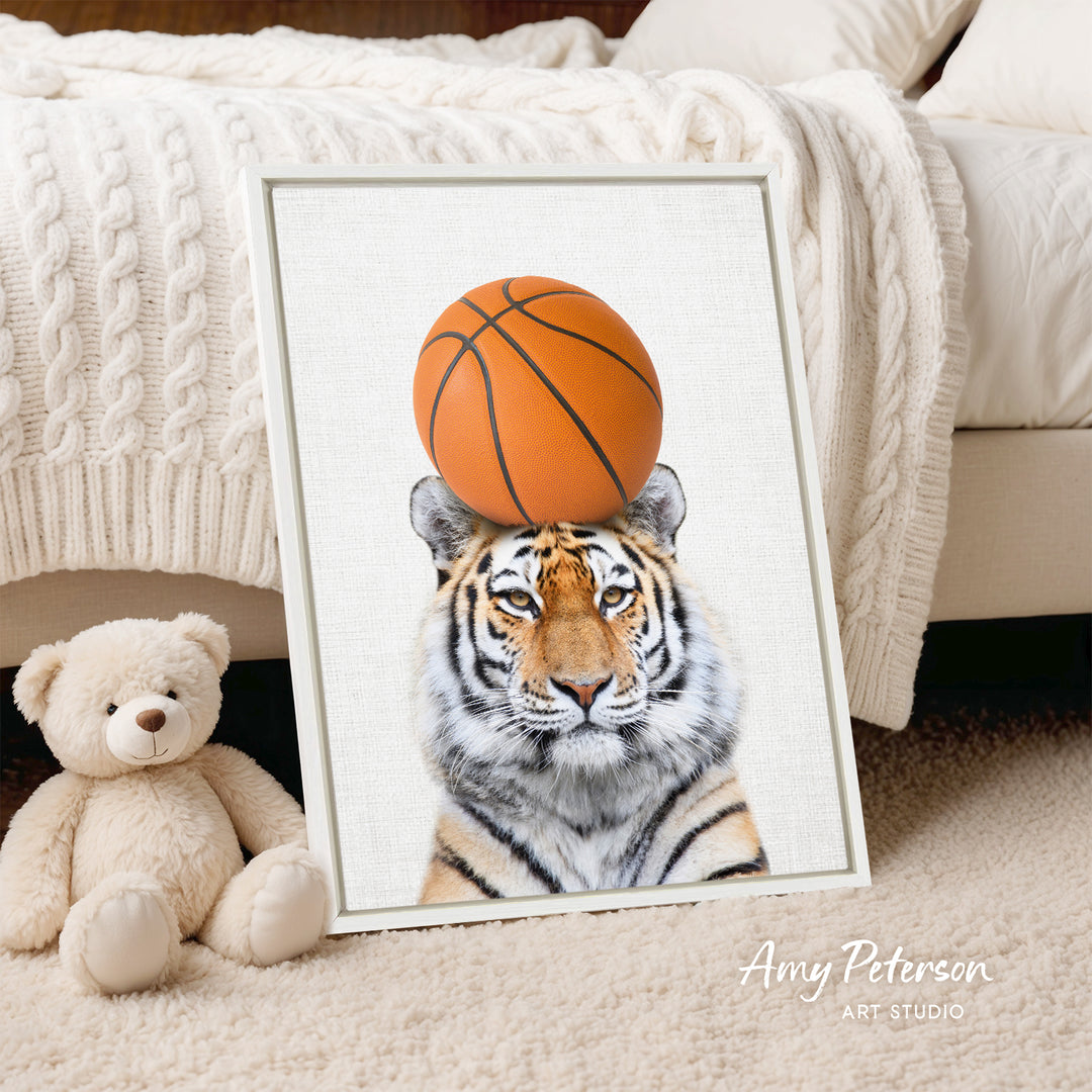 A framed print of a tiger's face with a basketball on its head is displayed on a bed, accompanied by a teddy bear.