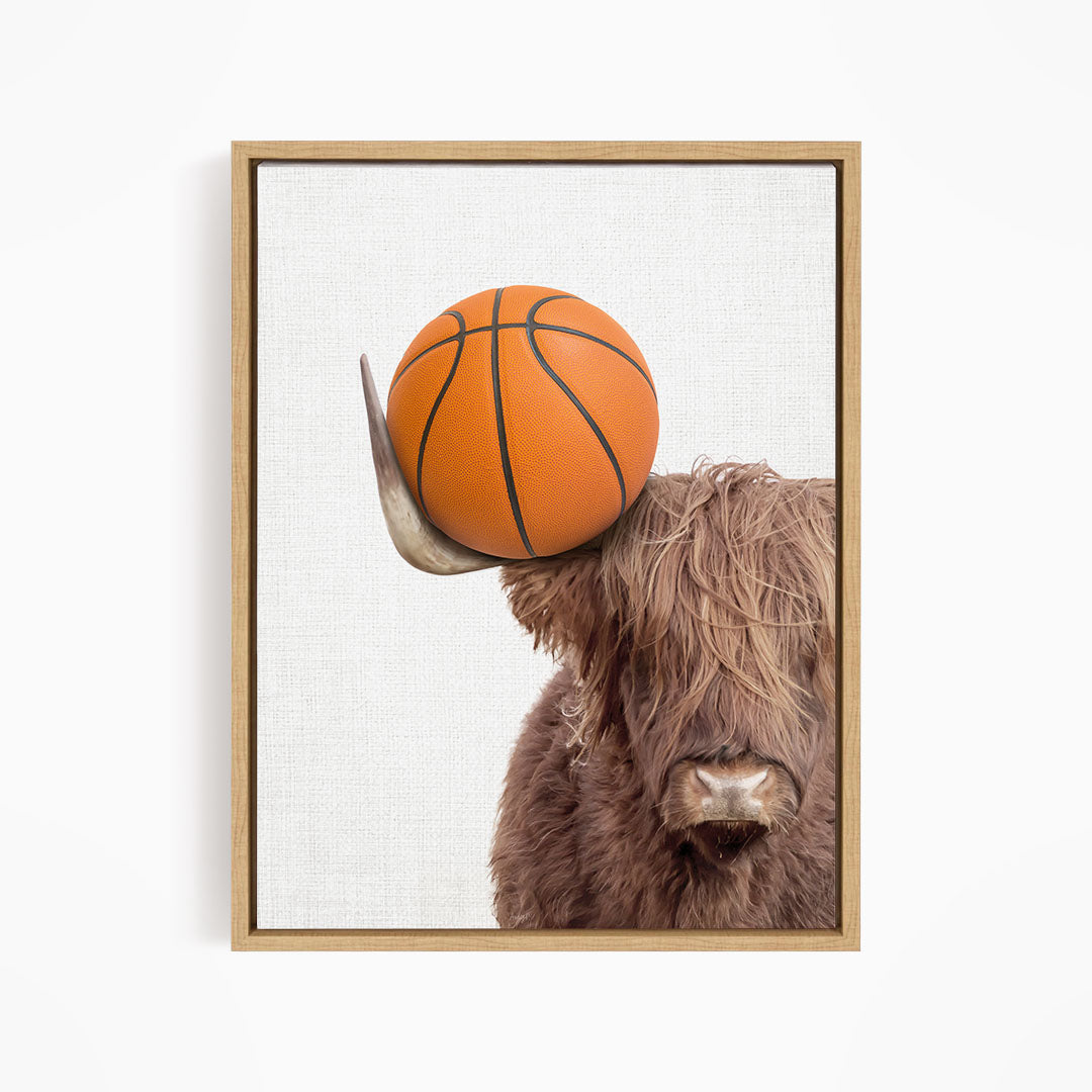 A brown cow with shaggy hair is holding a basketball on its head, creating a playful and whimsical scene.