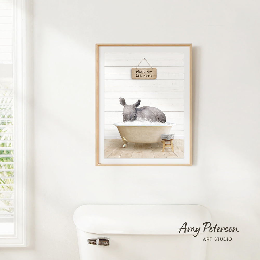 A framed watercolor painting of a rhinoceros sitting in a bathtub, with a sign above it that says "Wash Yer Self".