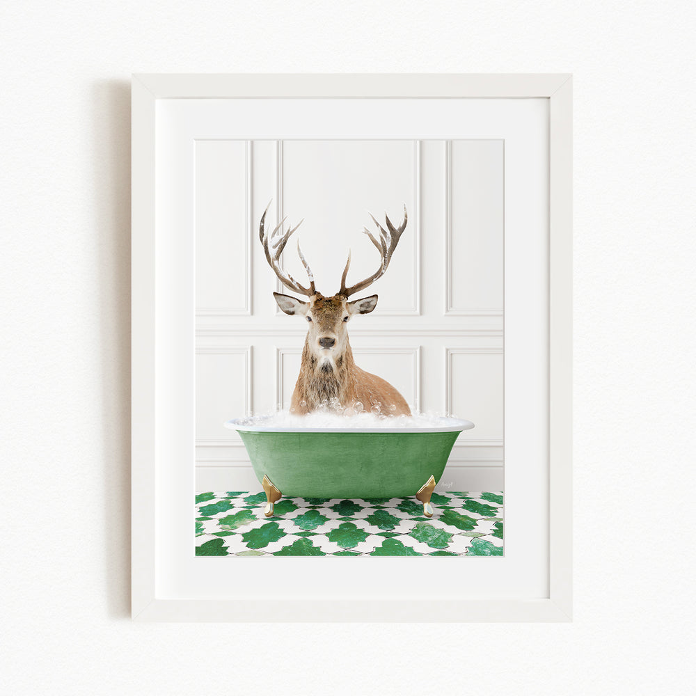 A deer with large antlers is sitting in a green bathtub filled with water, surrounded by a green and white patterned rug.