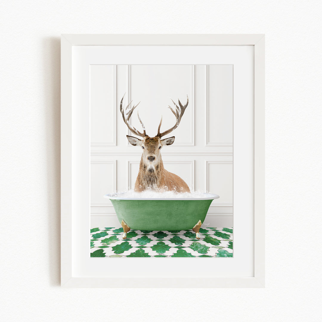 A deer with large antlers is sitting in a green bathtub filled with water, surrounded by a green and white patterned rug.