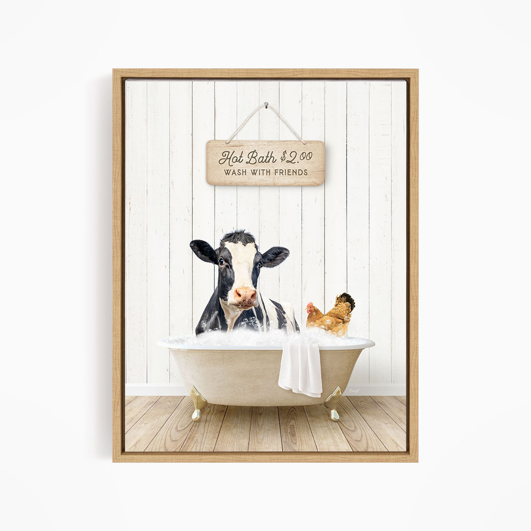 A framed image depicting a cow sitting in a bathtub, with a sign above it that reads "Hot Bath $2.00 WASH WITH FRIENDS".