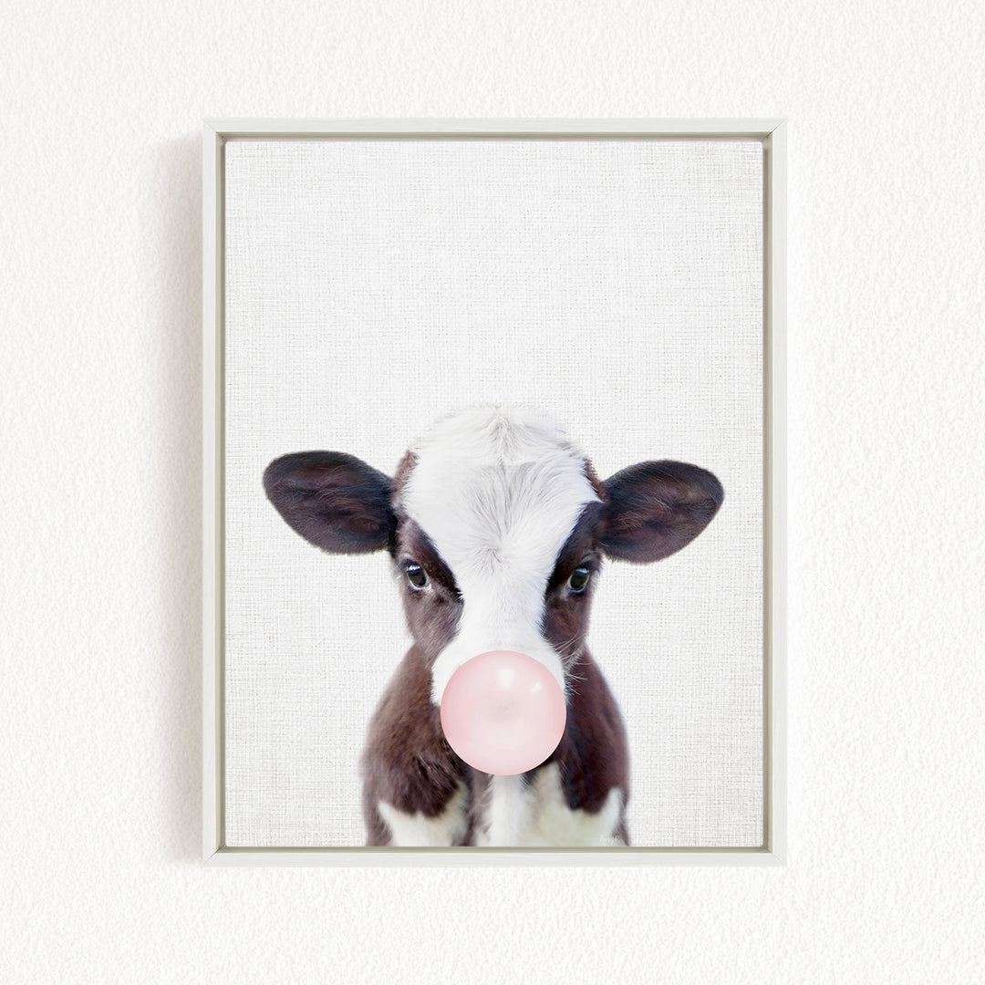 A black and white cow with a pink bubble in its mouth is the main subject of the image.
