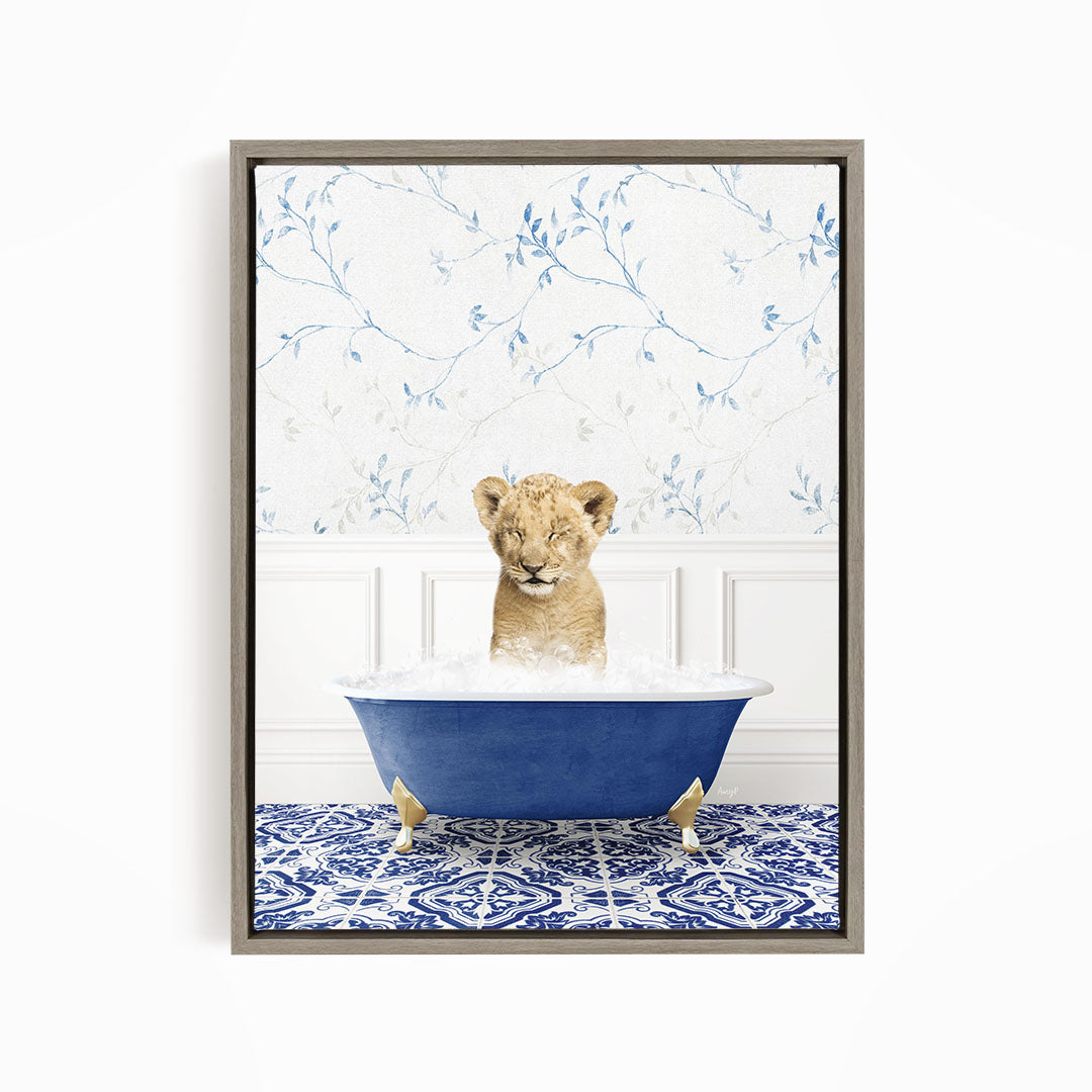 A young lion cub sitting in a blue bathtub filled with water, surrounded by a blue and white patterned rug.