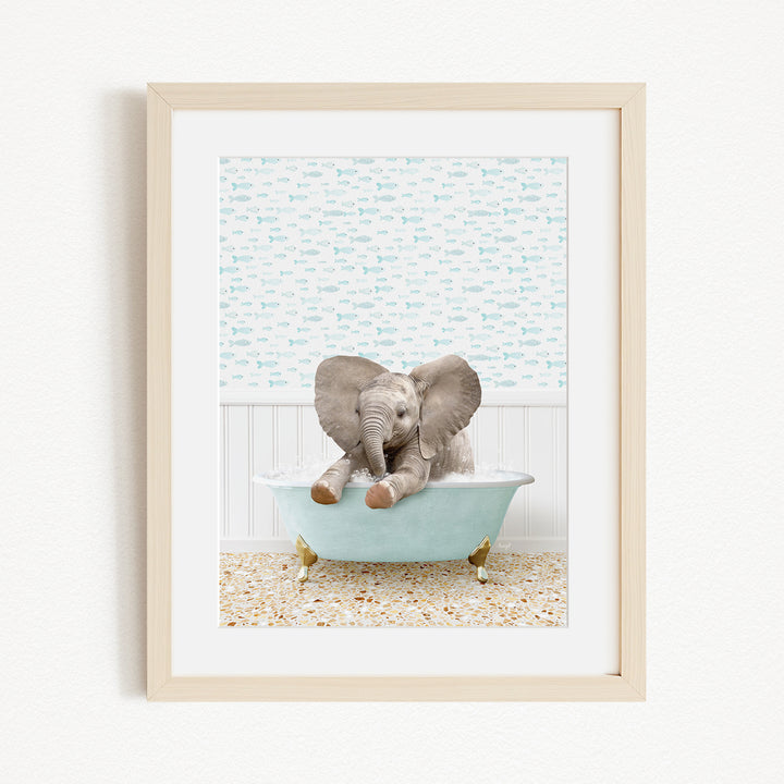 A baby elephant sitting in a light blue bathtub, with its trunk raised and ears flapping, against a background of blue and white fish.