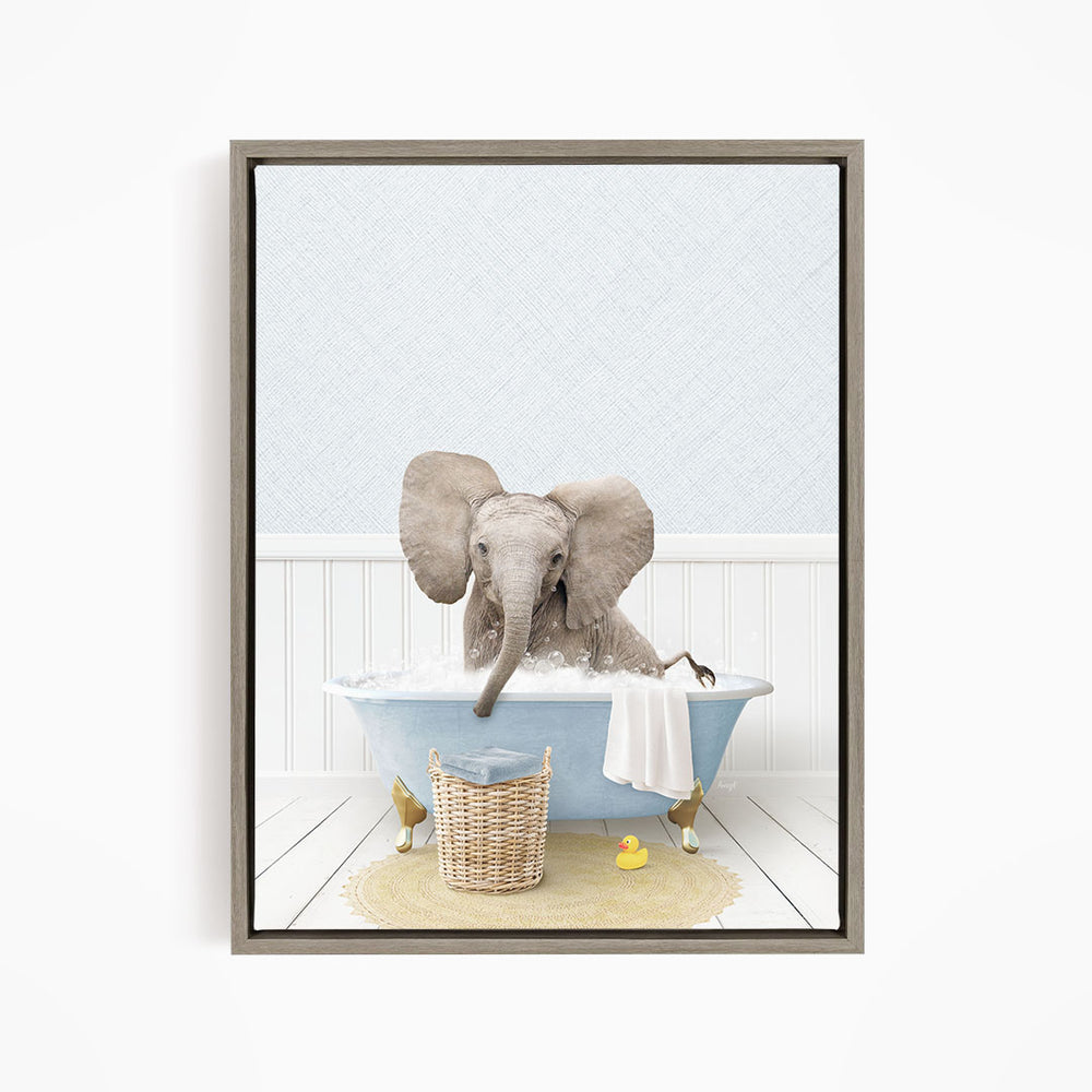 A gray elephant is sitting in a blue bathtub filled with water, surrounded by a yellow rubber duck and a basket.