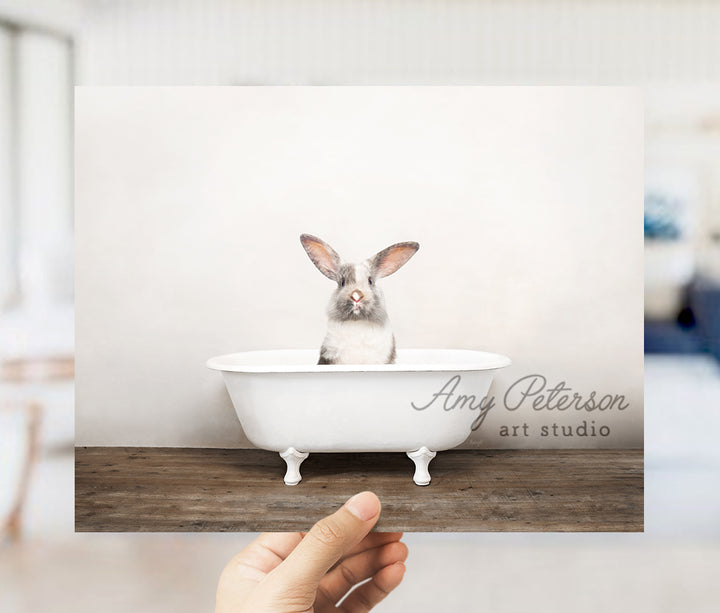 a person holding up a photo of a rabbit in a bathtub