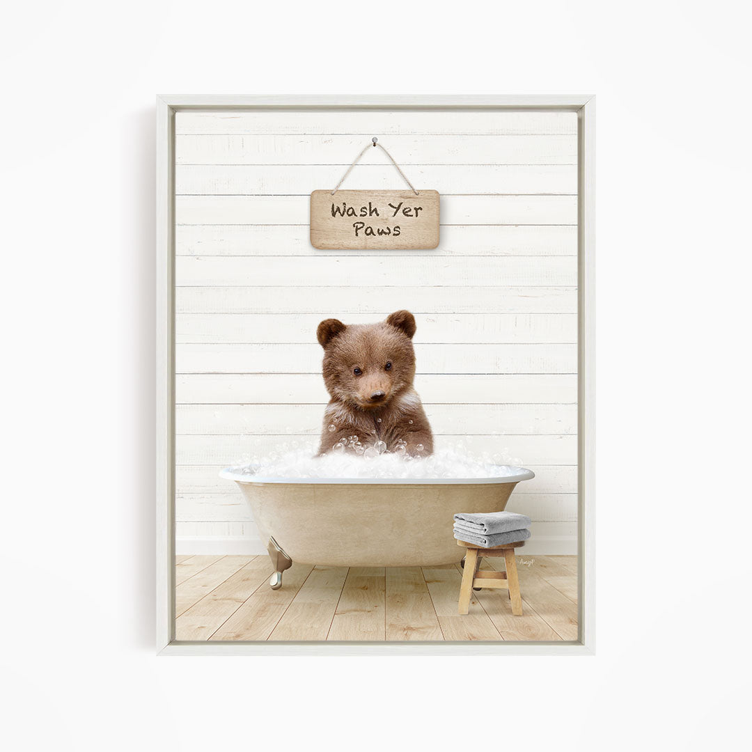 A brown bear sitting in a bathtub filled with water, with a sign above that says "Wash Your Paws".