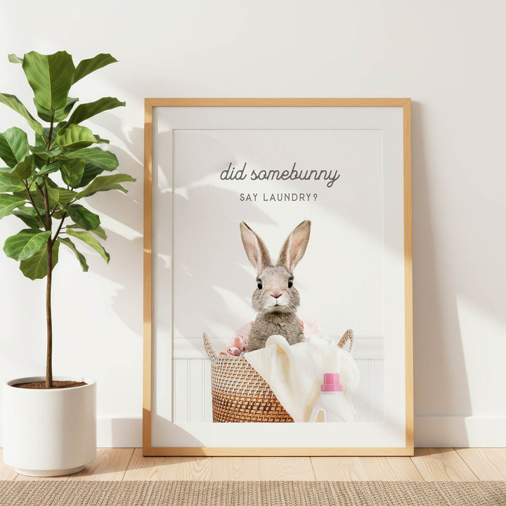 A framed poster with a picture of a rabbit sitting in a basket, accompanied by the text "did some bunny say laundry?".