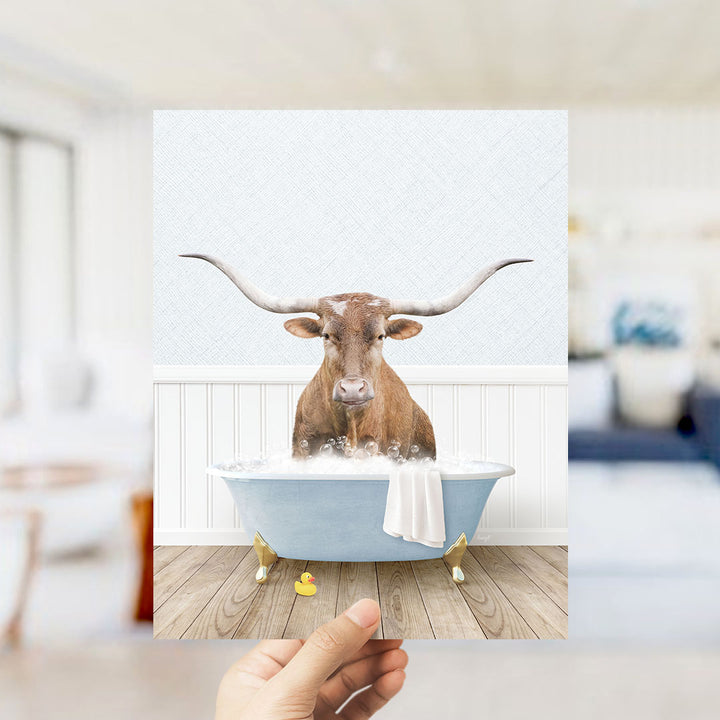 A brown bull with long horns is sitting in a blue bathtub filled with water, surrounded by a white wall and wooden floor.