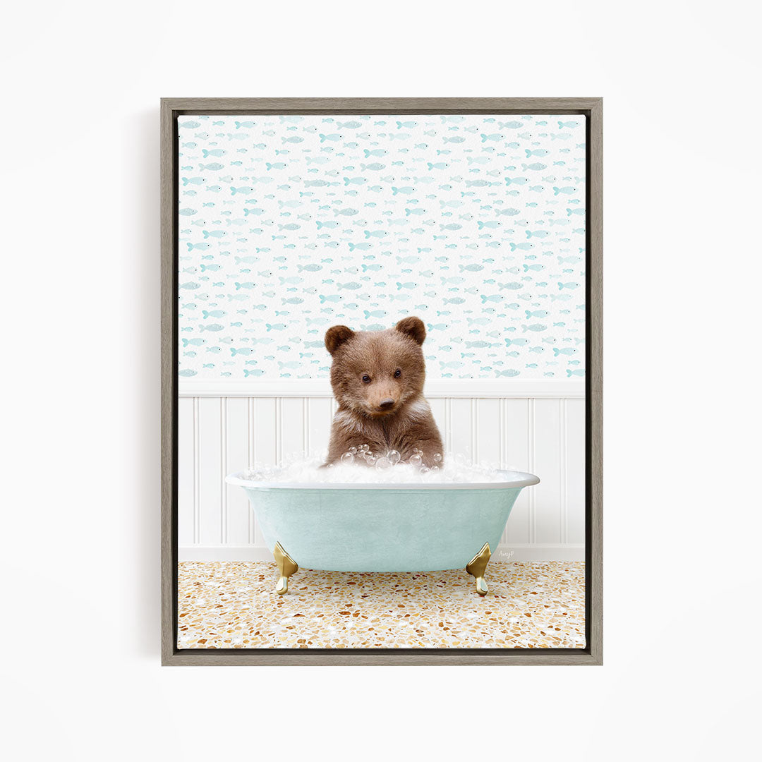 A cute brown bear sitting in a light blue bathtub filled with bubbles, surrounded by a pattern of fish.