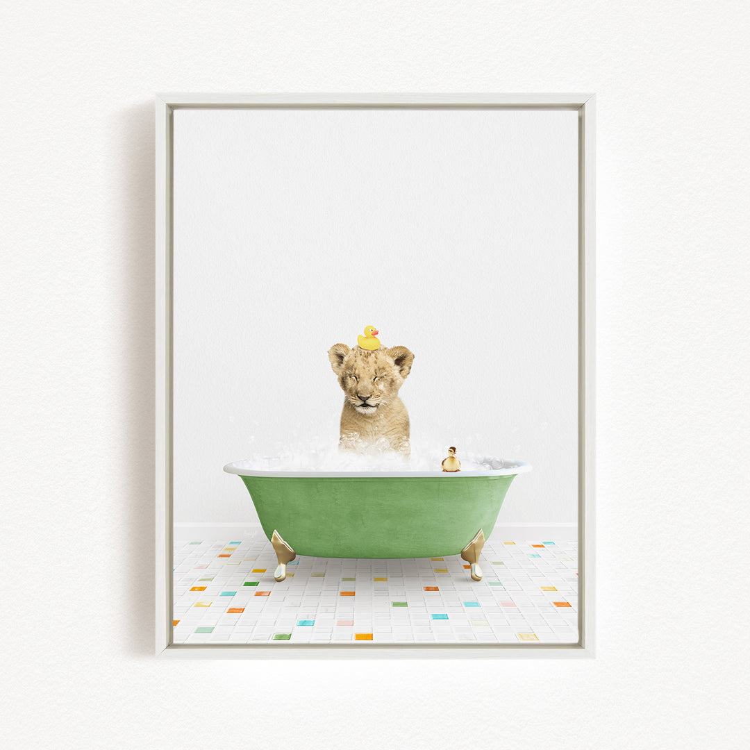 A young lion cub is sitting in a green bathtub filled with bubbles, with a yellow duck perched on its head.