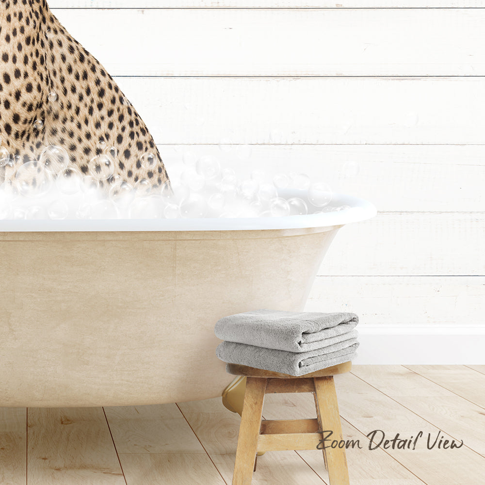 A leopard print towel is placed on a wooden stool next to a bathtub filled with bubbles, creating a cozy and relaxing atmosphere.