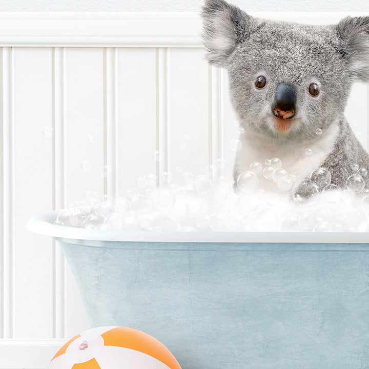 a koala in a bathtub with bubbles and a beach ball