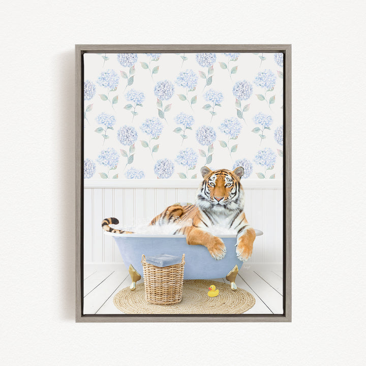 A tiger is sitting in a bathtub filled with water, surrounded by a blue and white floral patterned wallpaper and a basket of toys.