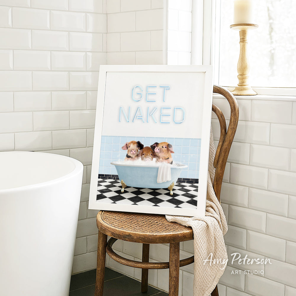 A framed print with a cartoon image of three pigs sitting in a bathtub, accompanied by the text "GET NAKED" in a playful, humorous font.
