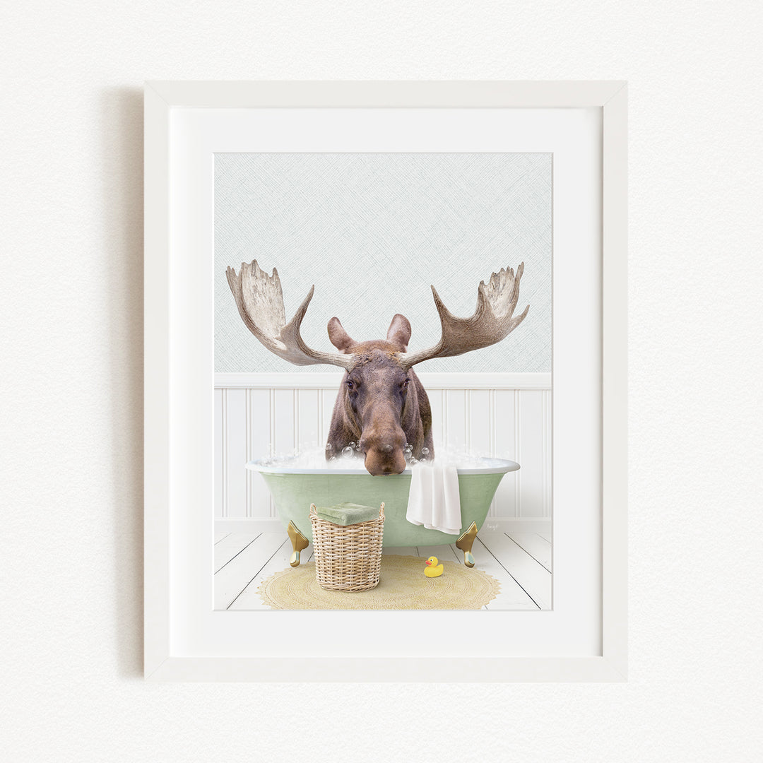 A moose with large antlers is sitting in a green bathtub, surrounded by a basket of rubber ducks and a yellow rubber ducky.