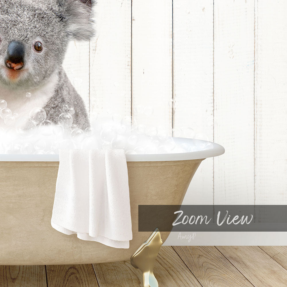 A koala bear sitting in a bathtub filled with bubbles, with a towel draped over the side.