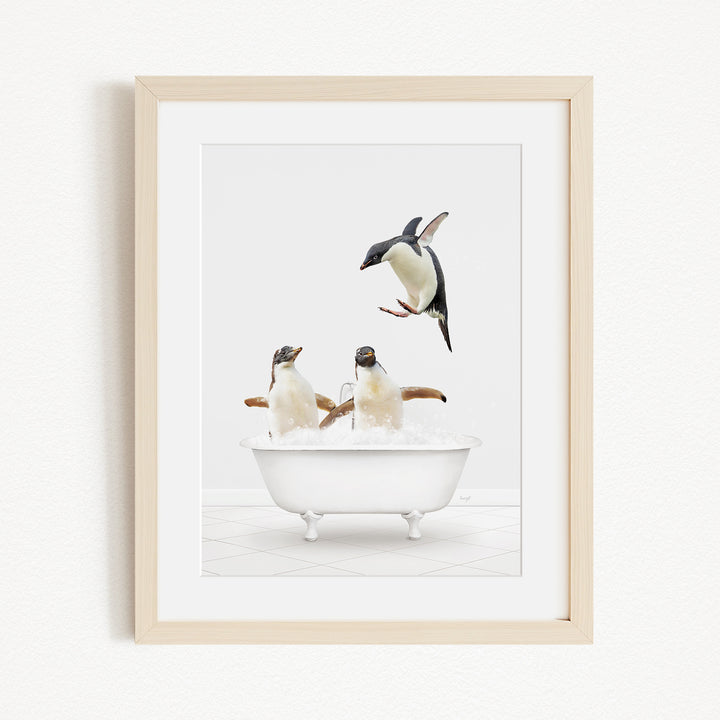A framed image depicting two penguins sitting in a bathtub, with one penguin flying towards the other penguin.
