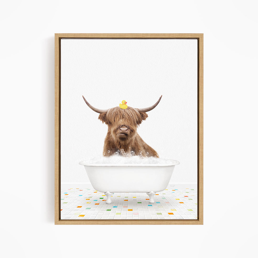 A brown cow with long horns is sitting in a white bathtub filled with bubbles, with a rubber duck perched on its head.