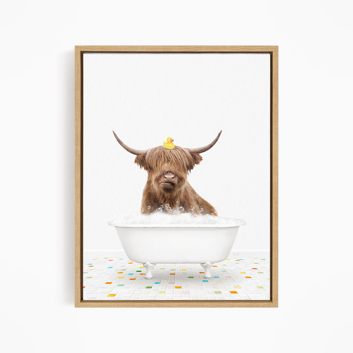 A brown cow with long horns is sitting in a white bathtub filled with bubbles, with a rubber duck perched on its head.