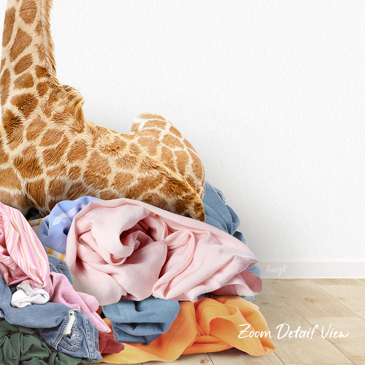 A pile of clothes, including a giraffe stuffed animal, is stacked on a wooden floor.