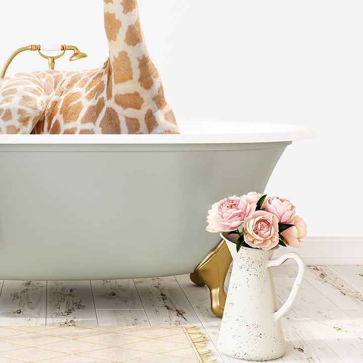 A giraffe is standing in a bathtub filled with water, surrounded by pink flowers and a white vase on a wooden floor.