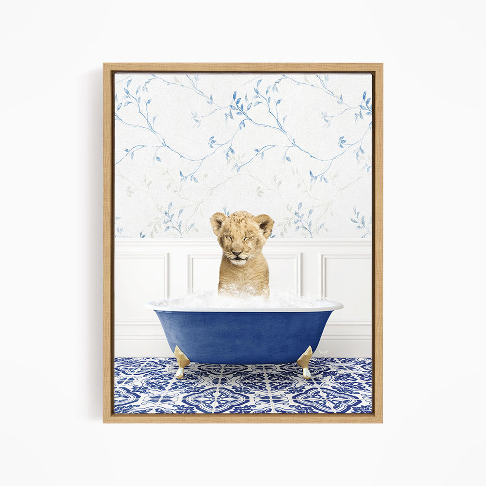 A young lion cub sitting in a blue bathtub filled with water, surrounded by a blue and white patterned rug.