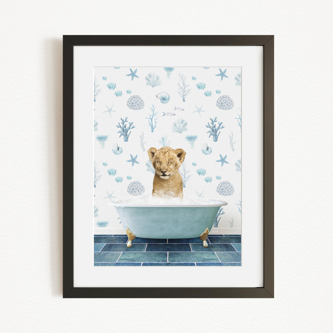 A young lion cub sitting in a bathtub filled with bubbles, surrounded by a blue and white ocean-themed wallpaper.