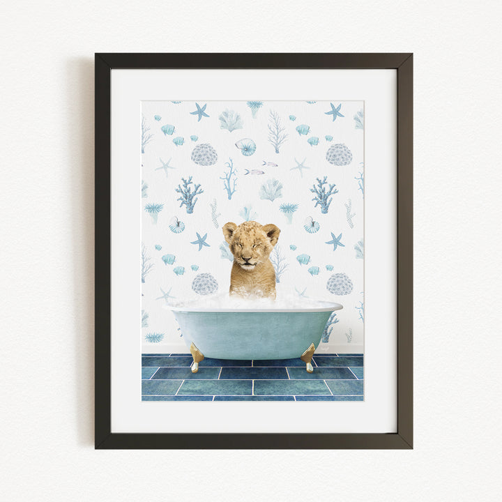 A young lion cub sitting in a bathtub filled with bubbles, surrounded by a blue and white ocean-themed wallpaper.