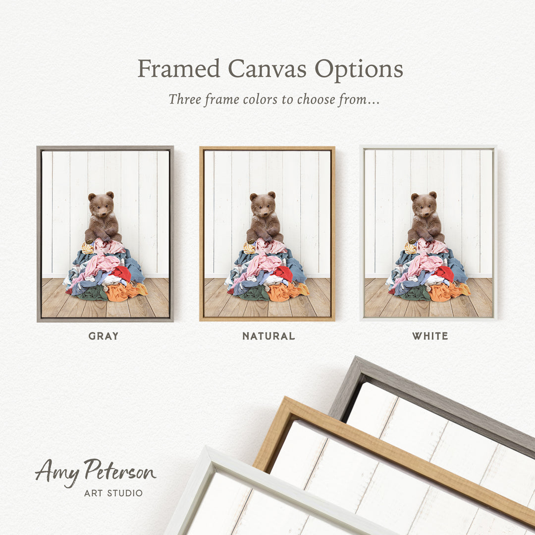 three framed canvas options, each featuring a teddy bear sitting on a pile of clothes. The options include a gray frame, a natural frame, and a white frame.
