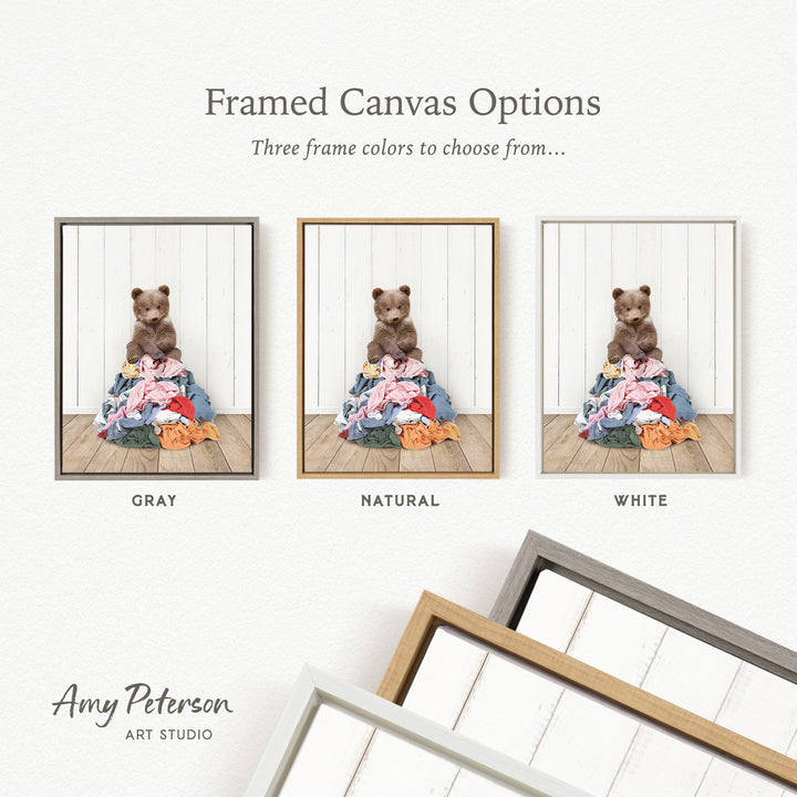 three framed canvas options, each featuring a teddy bear sitting on a pile of clothes. The options include a gray frame, a natural frame, and a white frame.