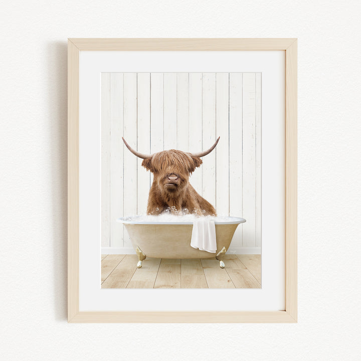 A brown Highland cow with large horns is sitting in a white bathtub, appearing to be enjoying a relaxing bath.