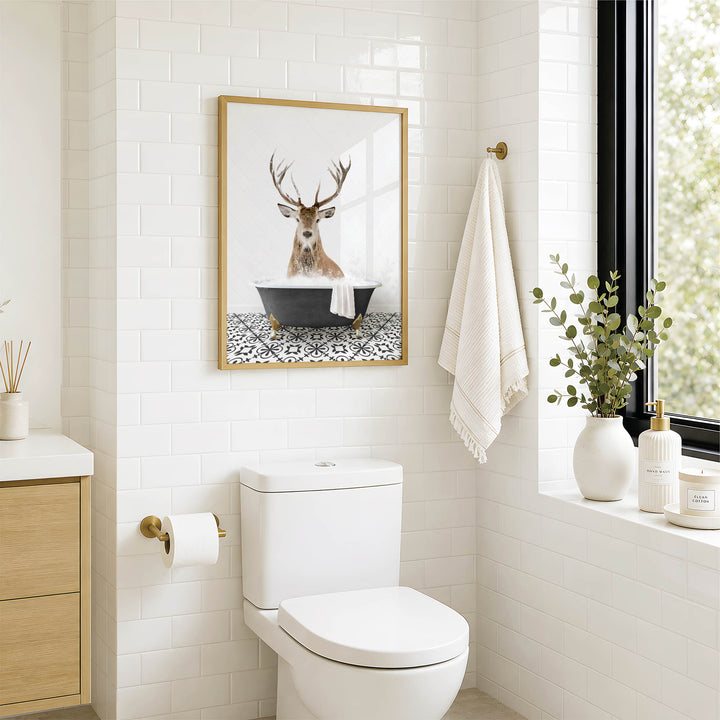 A bathroom with a white toilet, a framed picture of a deer in a bathtub, and a towel rack with a towel.