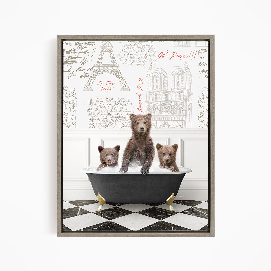 A framed image depicting three bears sitting in a bathtub, with a backdrop of the Eiffel Tower and other Parisian landmarks.