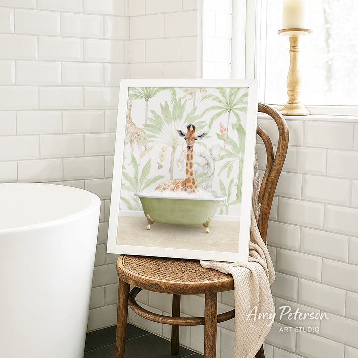 A framed image of a giraffe sitting in a bathtub, surrounded by tropical foliage, is displayed on a wooden chair in a bathroom setting.