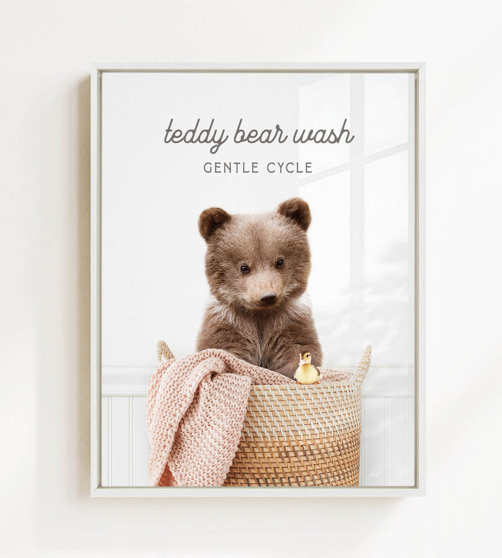 A teddy bear sitting in a woven basket, with a blanket and a toy duck nearby.