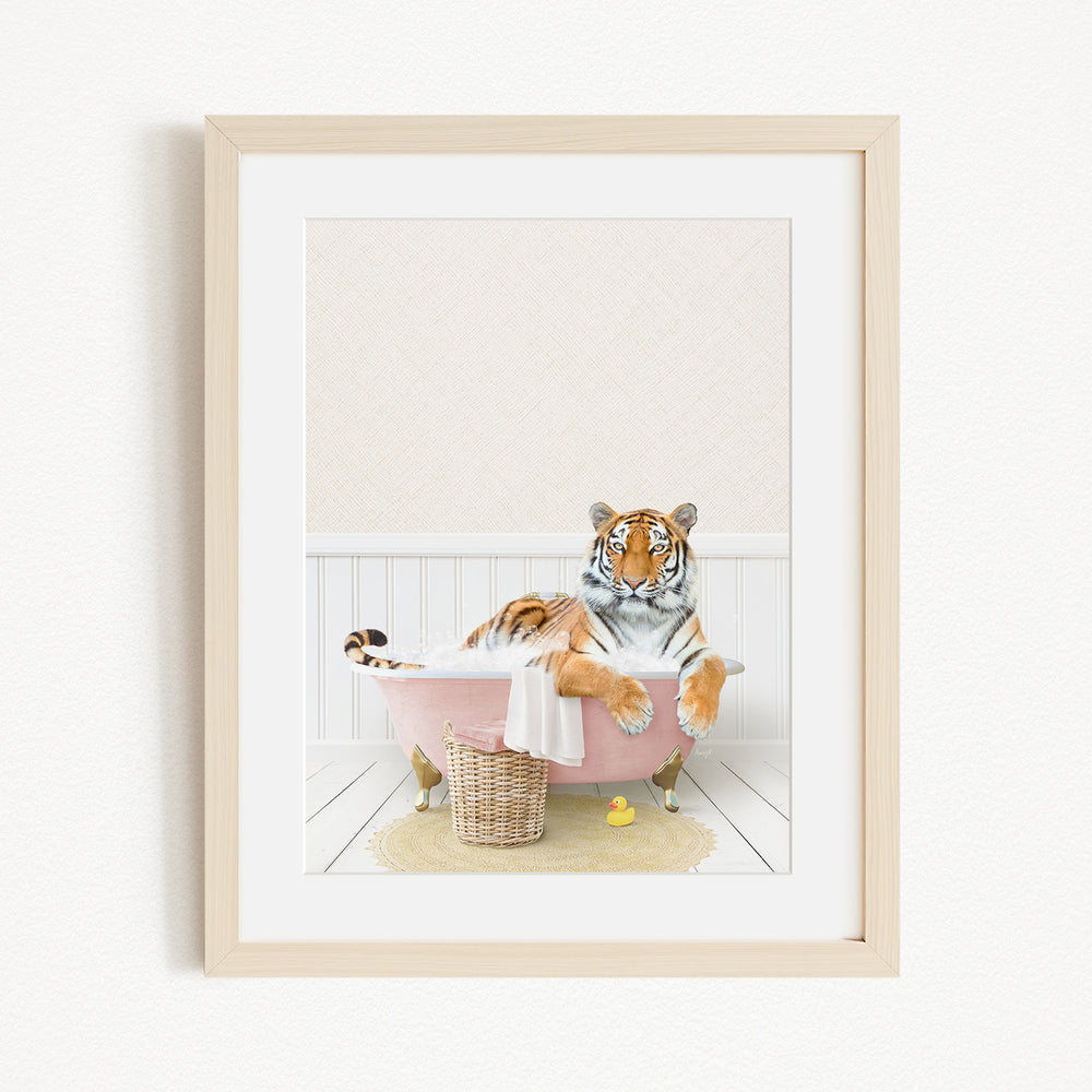A tiger is sitting in a pink bathtub, surrounded by a yellow rubber duck and a basket.