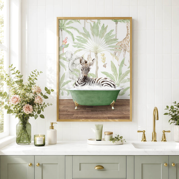 A framed painting of a zebra sitting in a green bathtub is displayed on a white wall above a bathroom sink with gold fixtures.