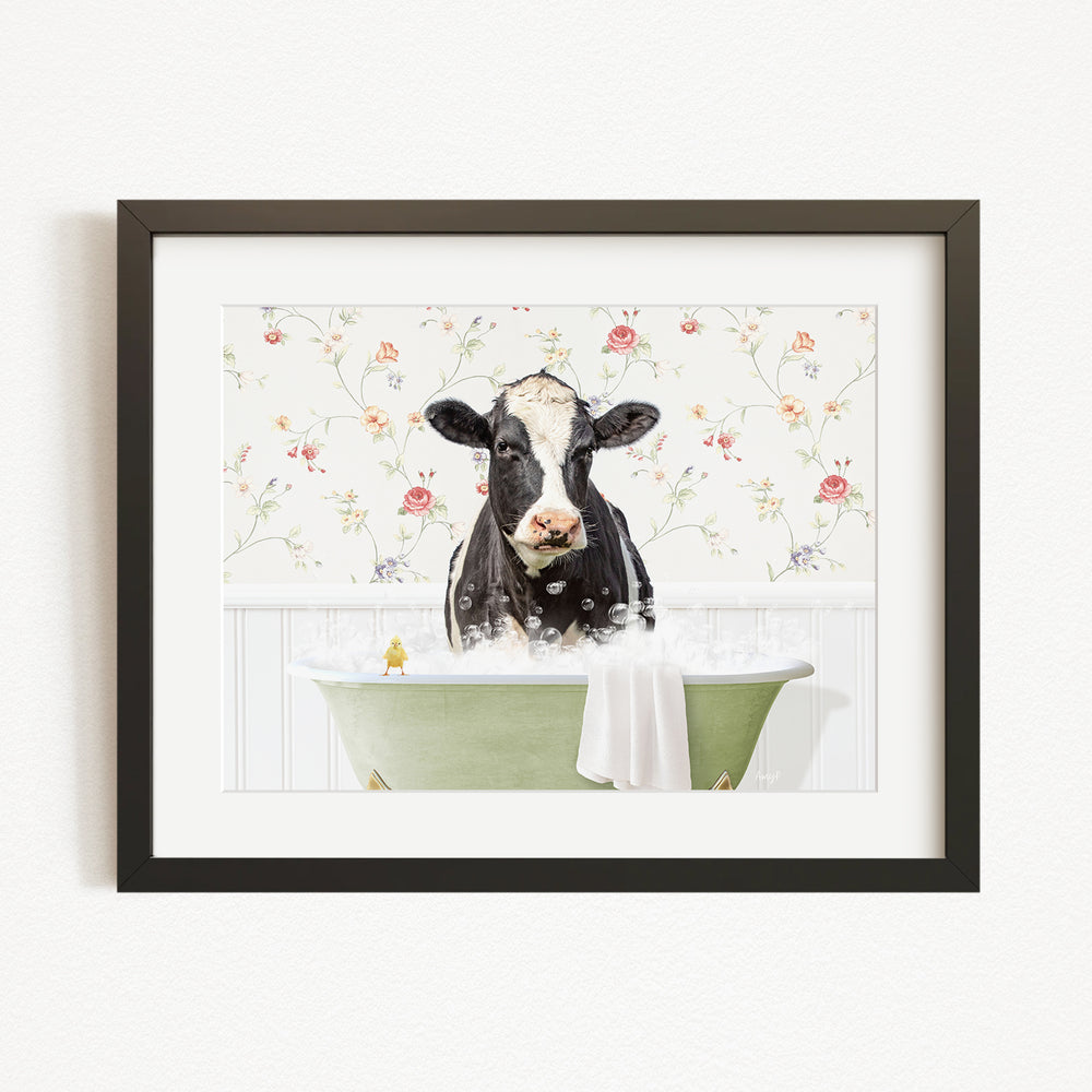 A black and white cow is sitting in a green bathtub filled with bubbles, surrounded by a floral patterned wall.