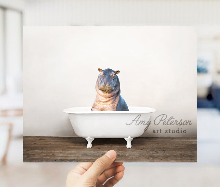 a person holding up a picture of a hippo in a bathtub