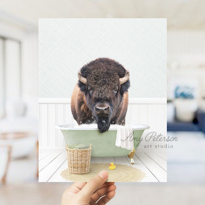 a person holding up a picture of a bison in a bathtub