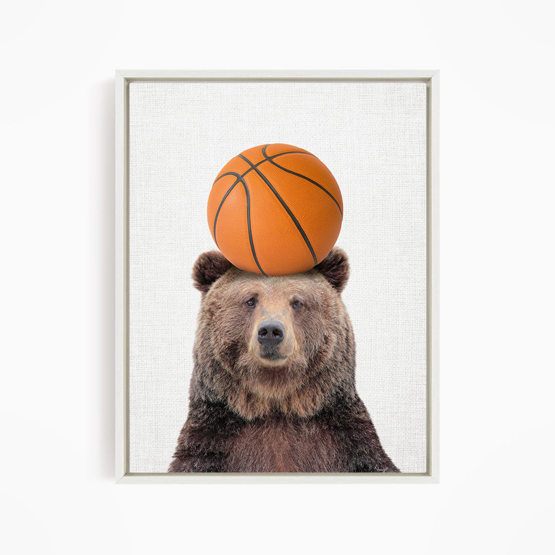 A brown bear balancing a basketball on its head.