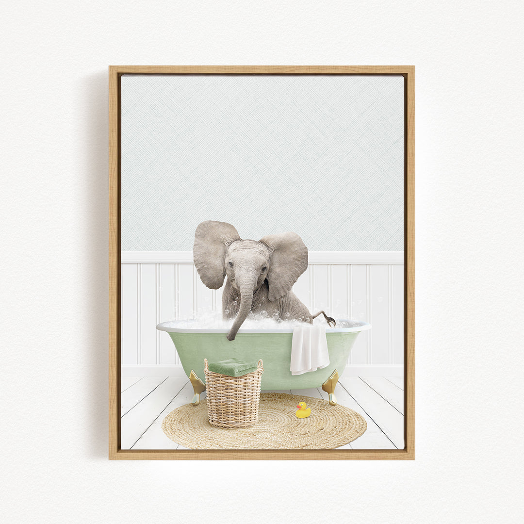 A baby elephant sitting in a green bathtub filled with water, surrounded by a basket of toys and a yellow rubber duck.